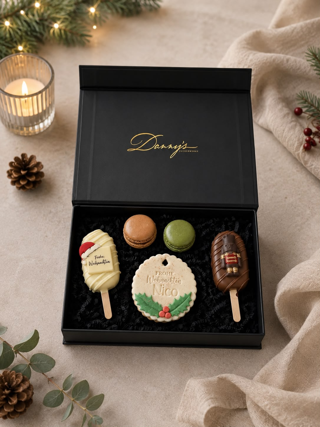 Geöffnete schwarze Weihnachtsbox mit Cakesicles, Macarons und personalisiertem Weihnachtskeks